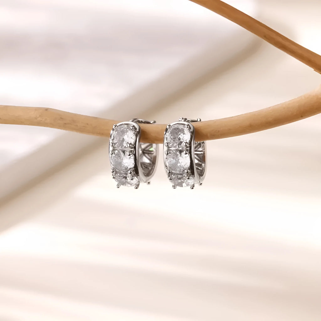 Close-up of a pair of silver U-shaped clip-on earrings for women with inlaid sparkling zircon stones.