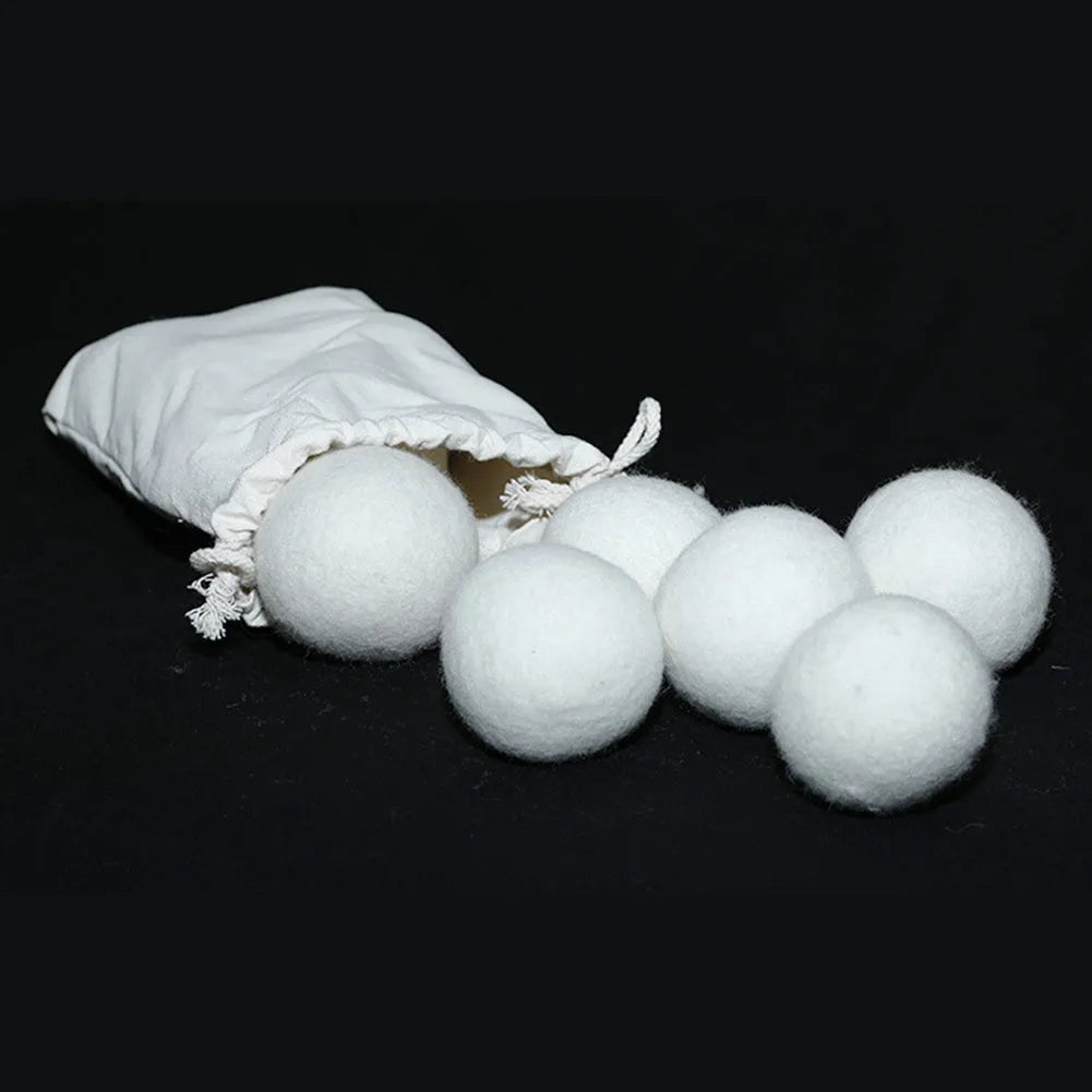 Set of wool laundry drying balls next to cotton storage bag for tumble dryers