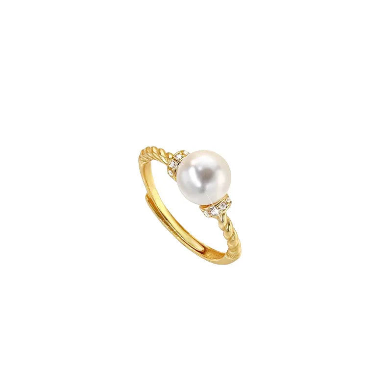 Close-up of an adjustable geometric twist ring in copper with a central pearl inlay, shown on a finger.
