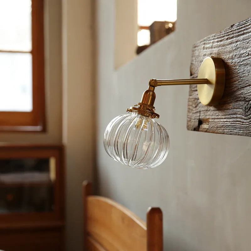 Pumpkin-shaped glass wall lamp in blue and transparent water ripple finishes mounted on a wall.