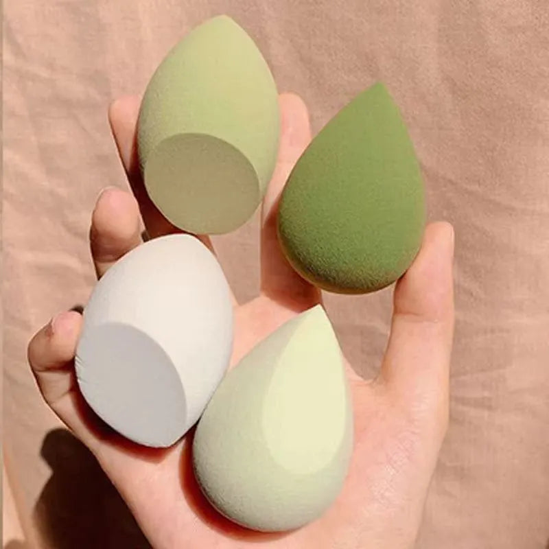 Set of seven coloured makeup sponges in different shapes on a pink background
