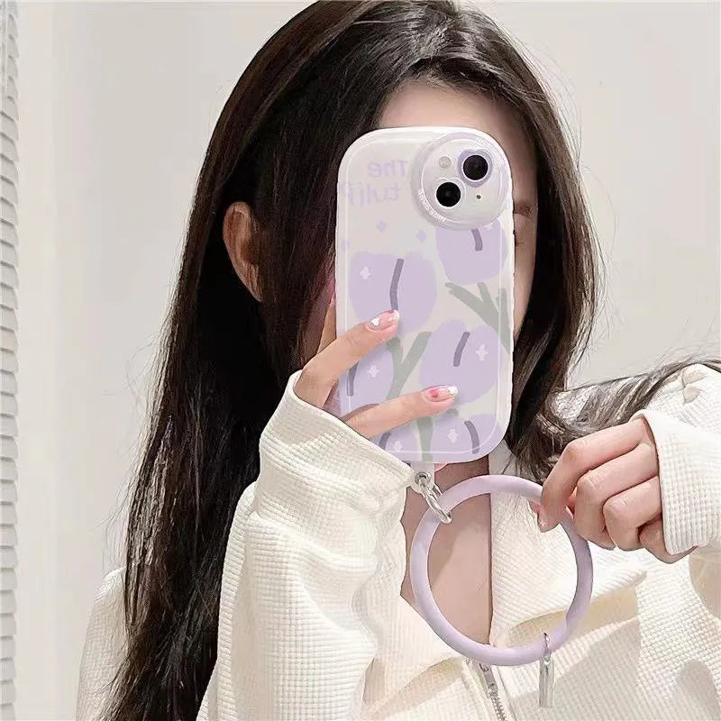 Clear purple tulip printed iPhone case with attached adjustable wrist strap on a table.