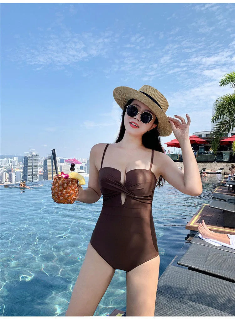 Simple solid colour one-piece swimsuit with spaghetti straps and push-up design in white, pink, or brown.