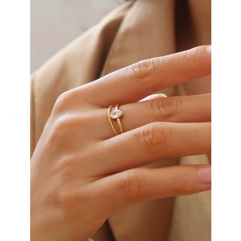 Gold heart-shaped ring and gold oval ring on display, both in stainless steel for women.