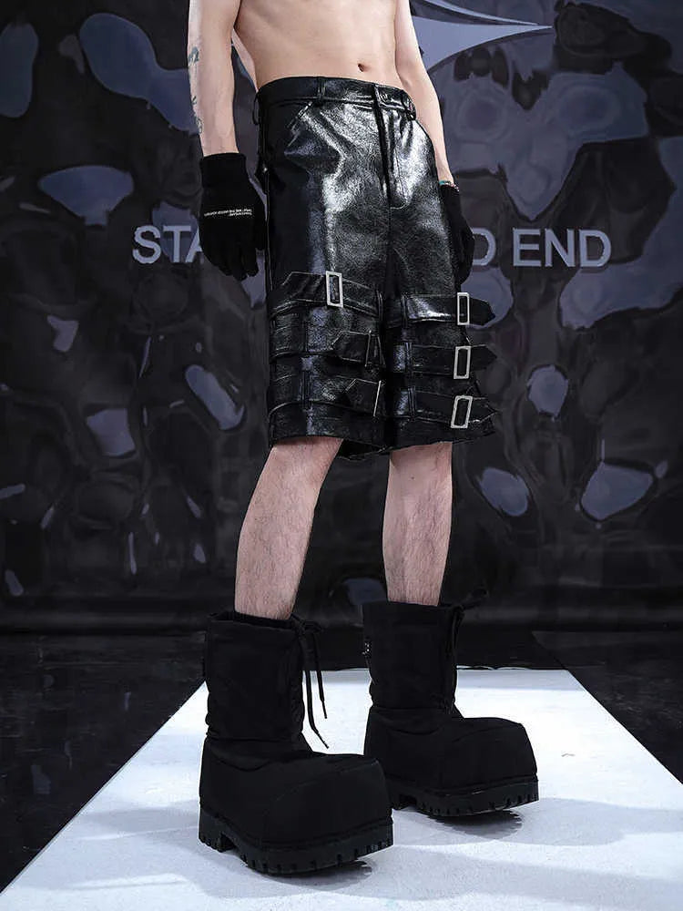 Black men's cropped PU leather shorts with ring detail on a hanger