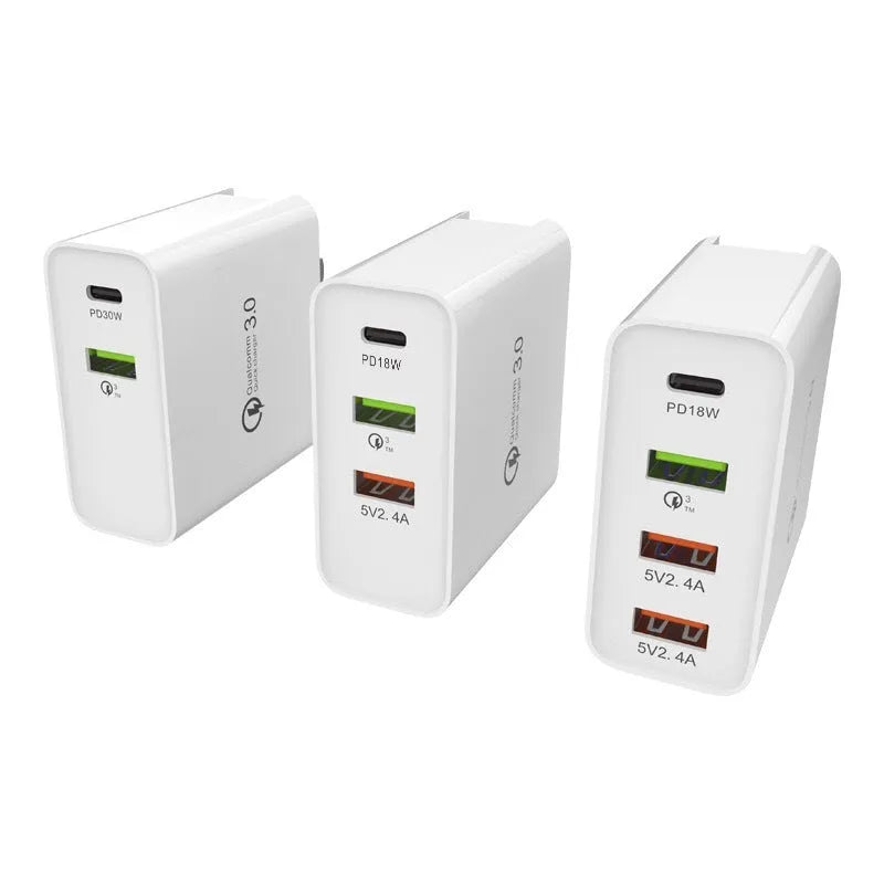 A white multi-port USB fast charger with UK plug and multiple USB-C and USB-A ports on a wooden table.