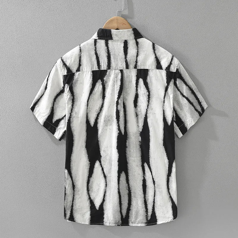 A man wearing a black and white retro striped loose-fit short sleeve cotton shirt.