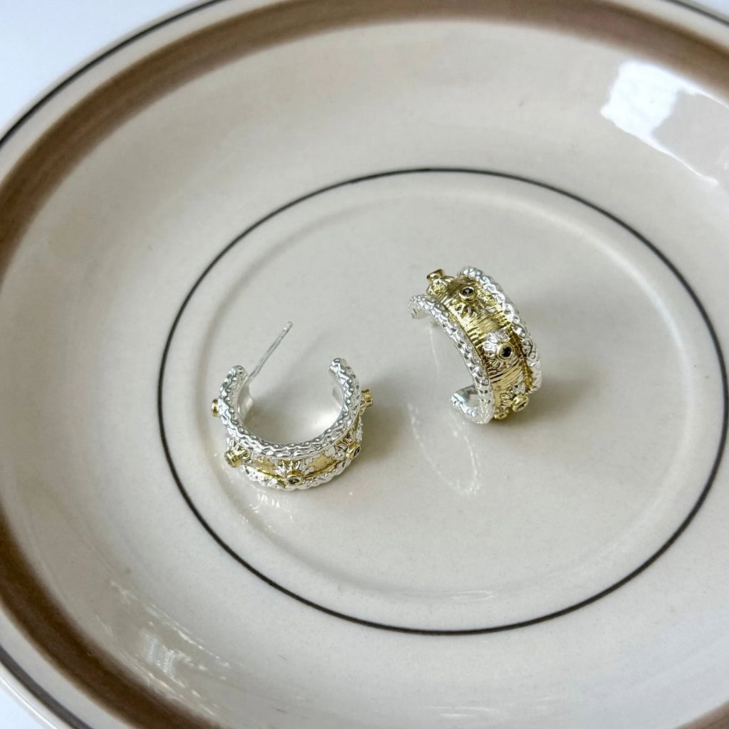 Gold and silver C-shaped brushed ring earrings on display, copper with 925 silver needles