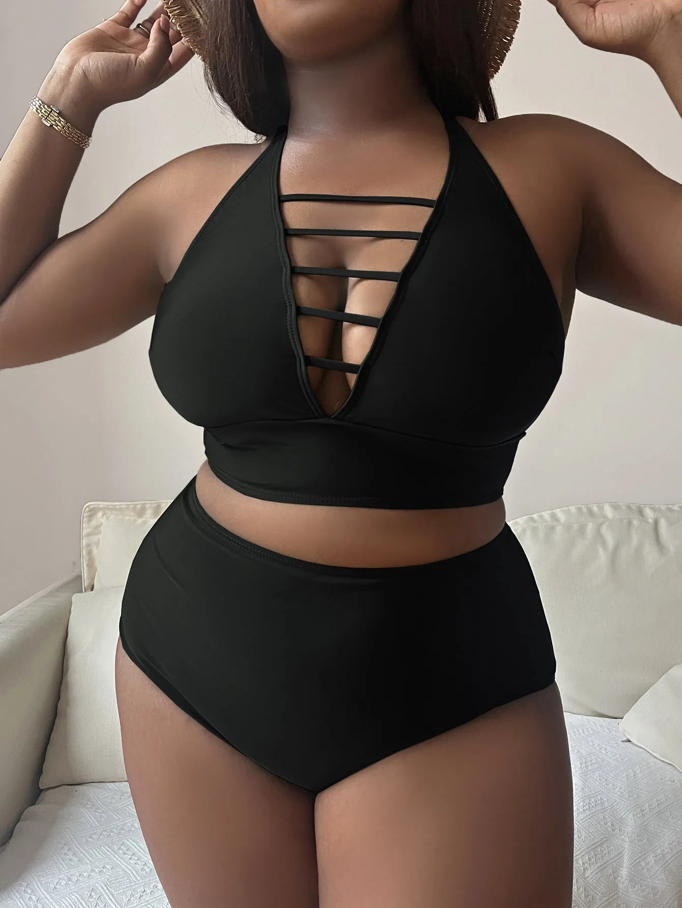 Plus size woman modelling a black halter bikini with adjustable cross straps and high-waisted briefs.