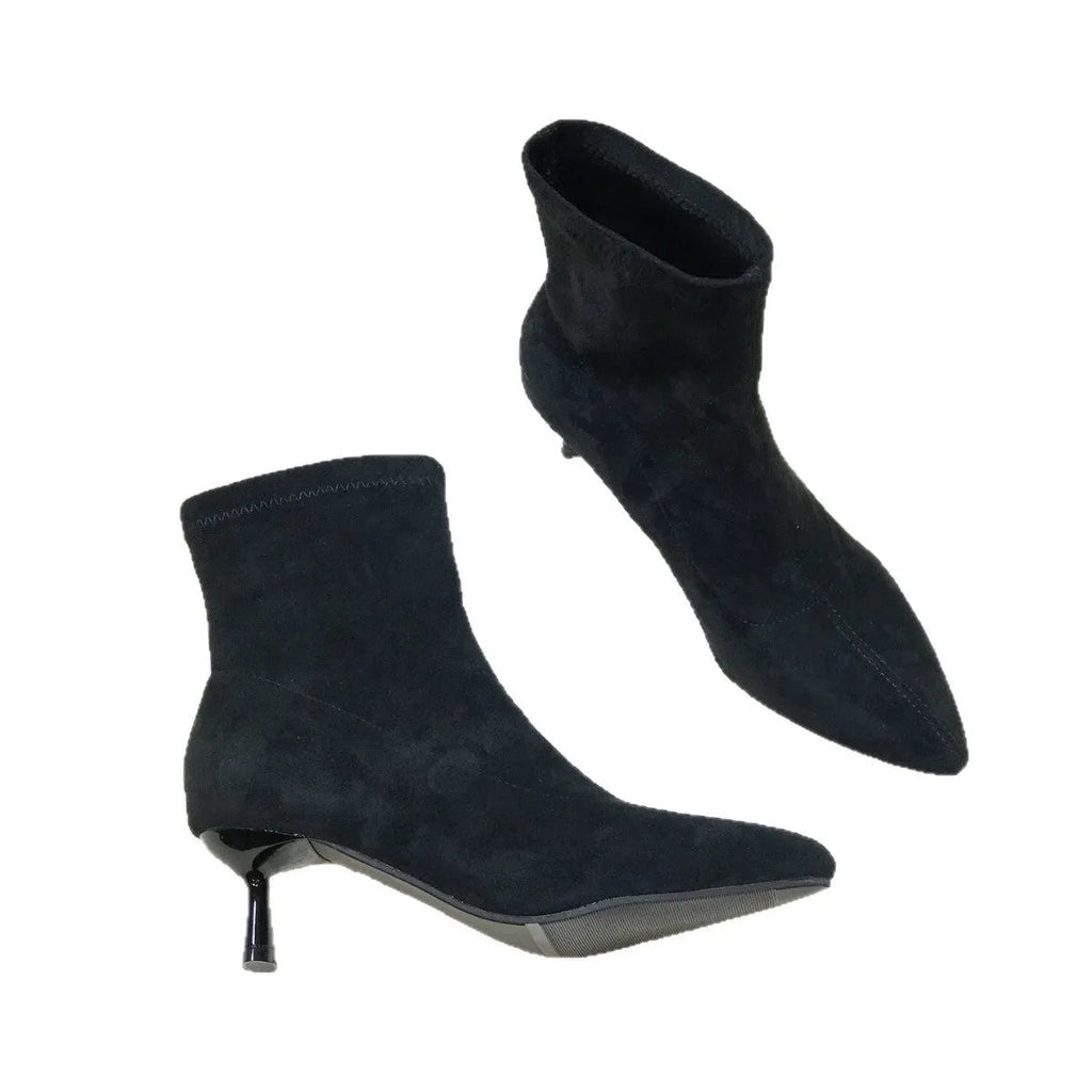 Black pointed toe women's ankle boot with a stiletto heel on a plain background.