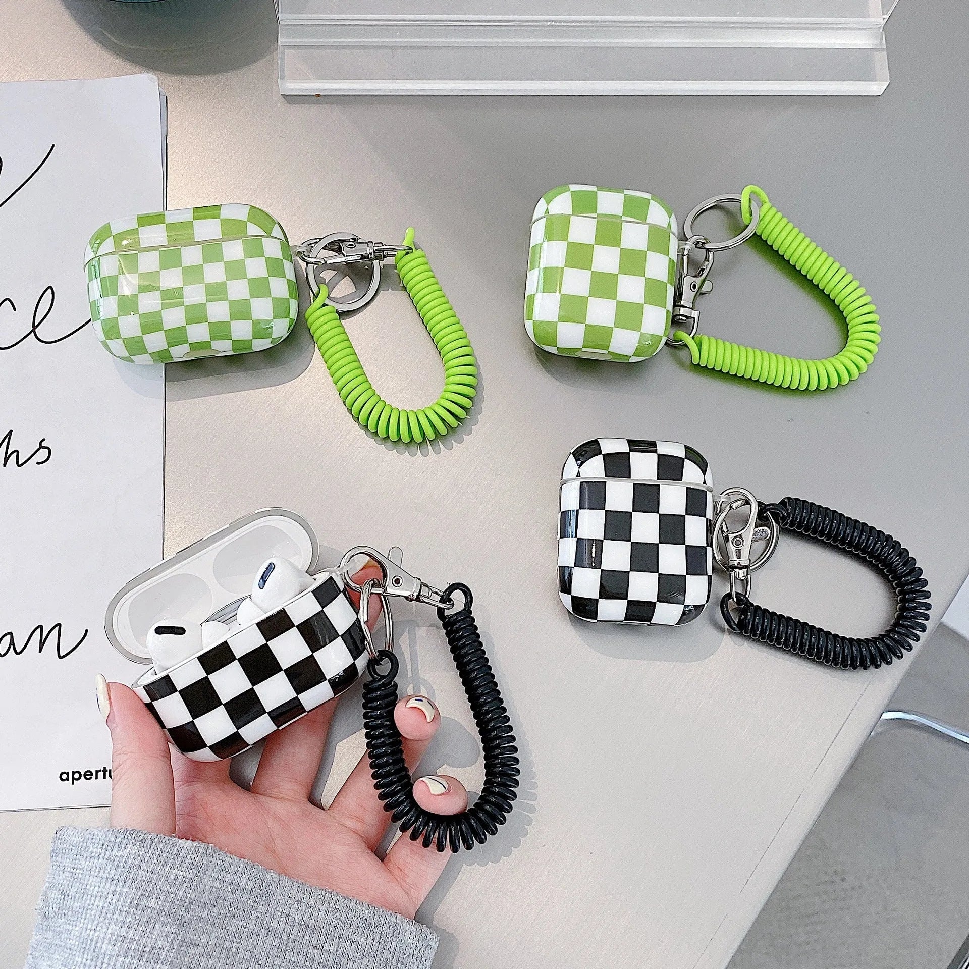 Black and green checkerboard pattern TPU protective case for Apple AirPods with optional smiley face lanyard.