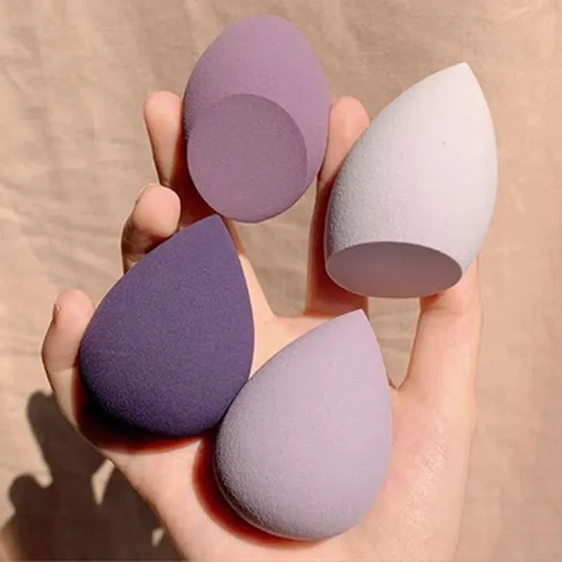 Set of seven coloured makeup sponges in different shapes on a pink background