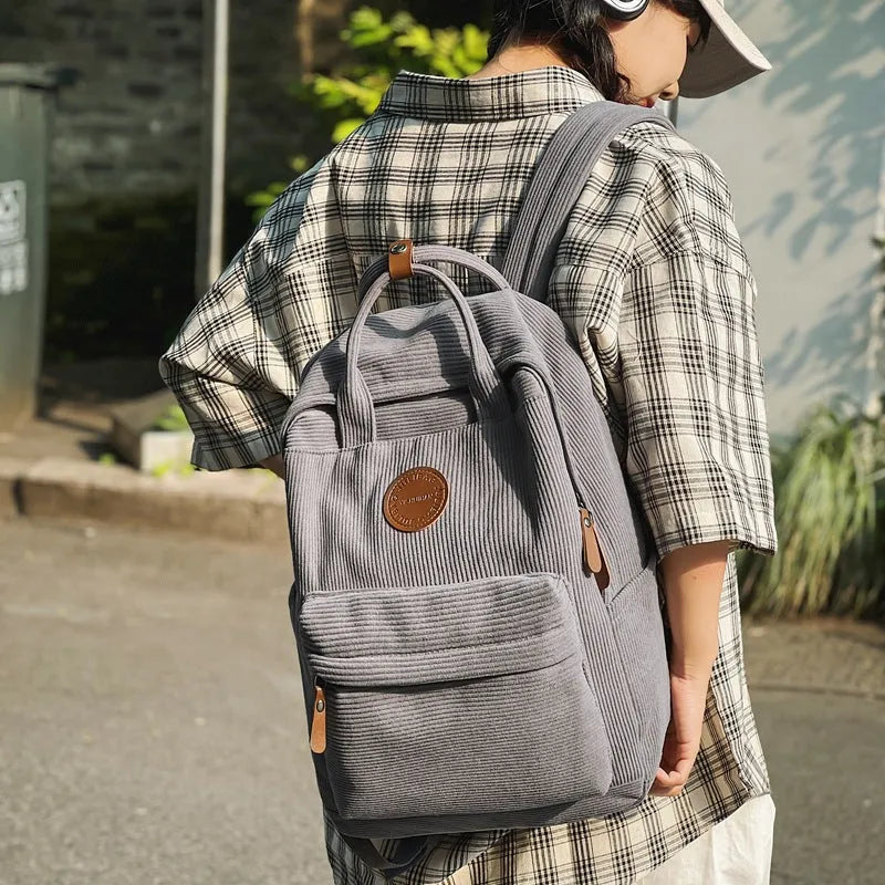 Retro unisex corduroy backpack in solid colour with breathable fabric, side view.