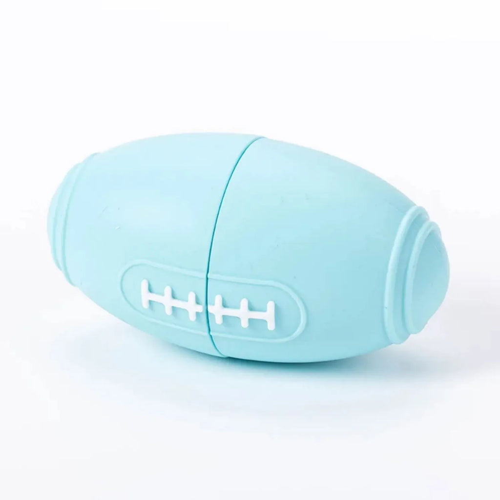 Blue silicone rugby ball dog toy with hollow treat compartment on a wooden floor
