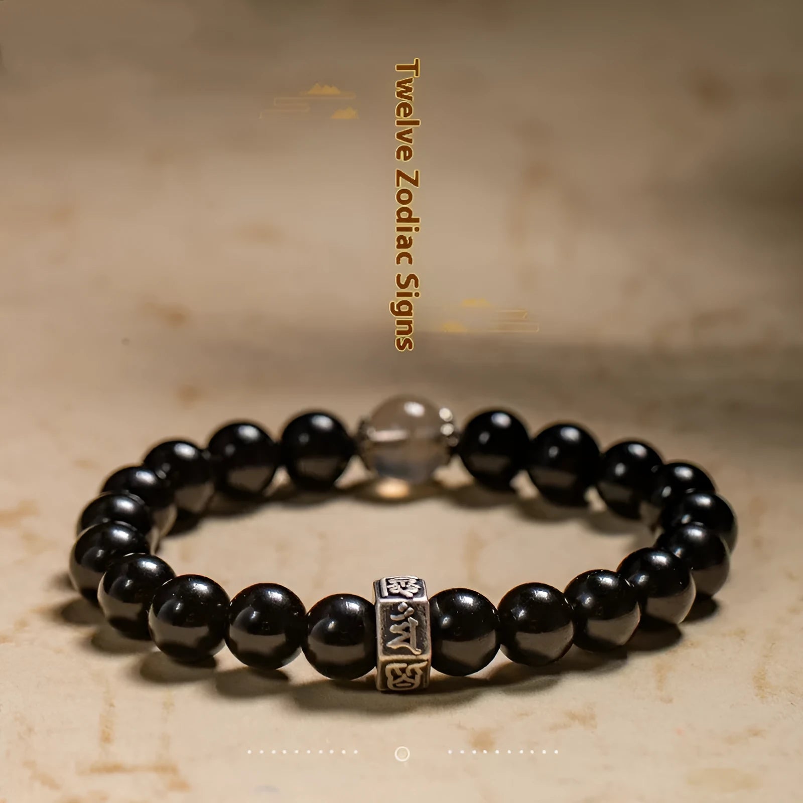 Obsidian bead bracelet with a hand-carved zodiac animal and bodhisattva charm on a wrist.