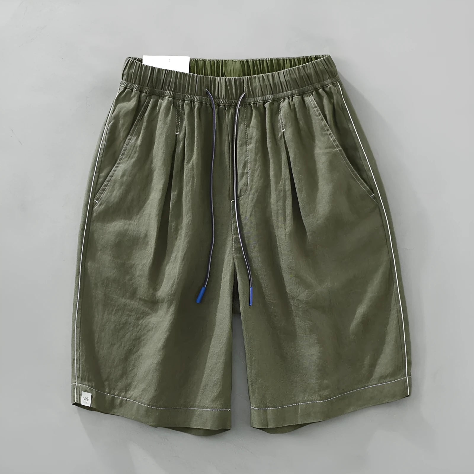 Man wearing loose fit green linen shorts with a straight leg and drawstring waist for casual summer wear.