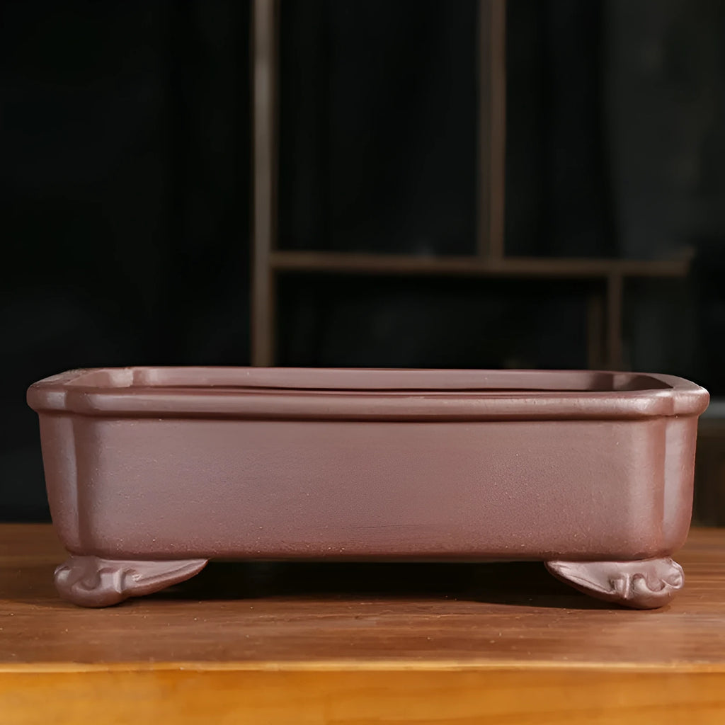 Rectangular antique purple sand bonsai pot with cut corners on a floor.