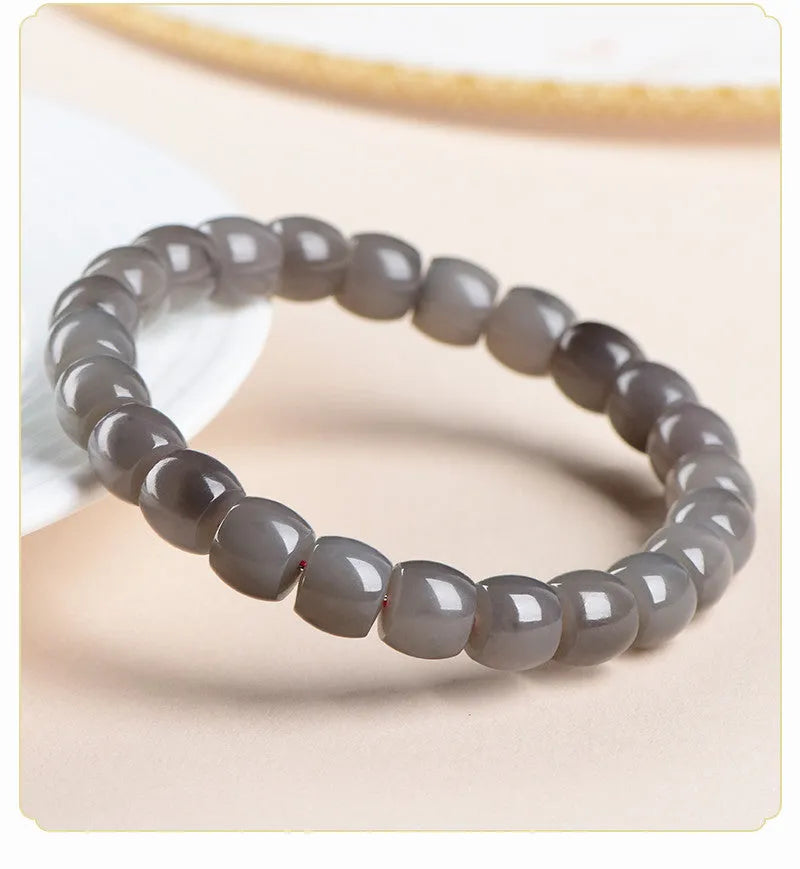 Straight cut Hetian jade bracelet in natural smokey violet colour on a wrist, showing polished 8x9mm beads.