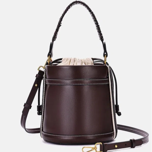 Brown PU cylindrical tote bag with dual handles, cross-body strap, and woven stitch detailing on a white background
