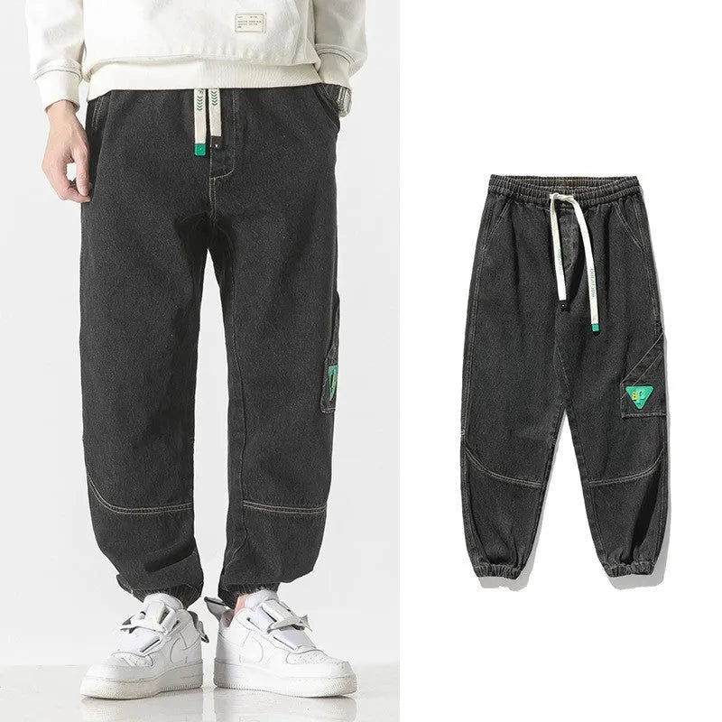 Men's loose-fit tapered cotton trousers in grey, shown laid flat, highlighting the tapered leg silhouette.