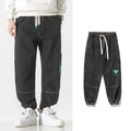 Men's loose-fit tapered cotton trousers in grey, shown laid flat, highlighting the tapered leg silhouette.