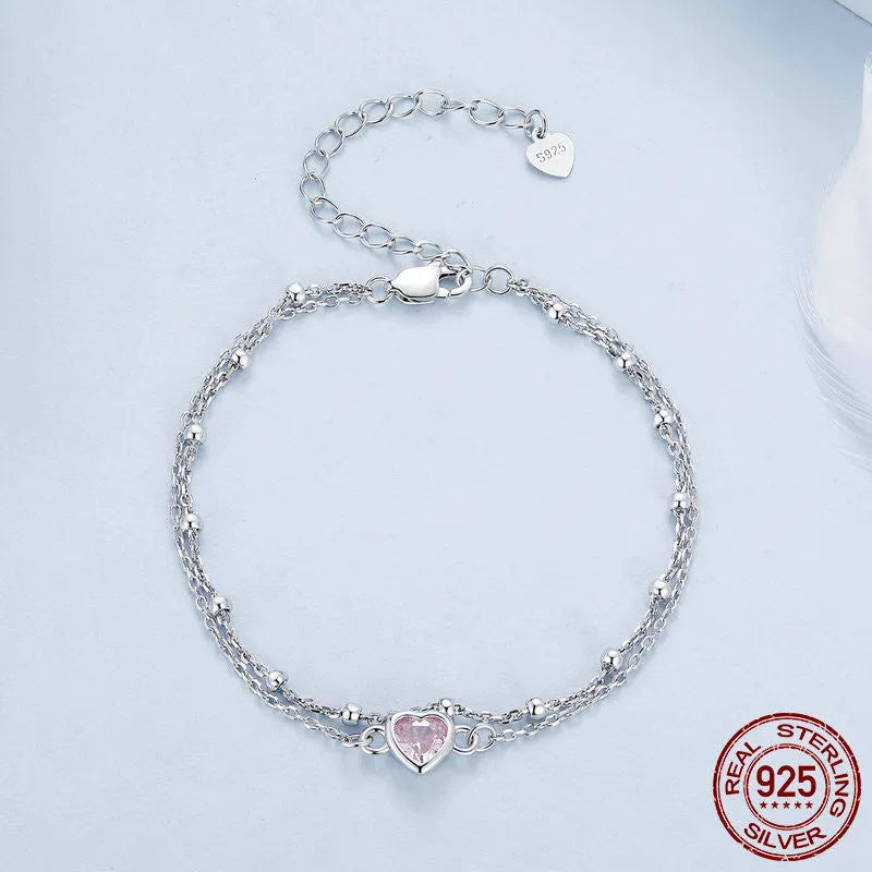 Close-up of a sweet girlish style sterling silver bracelet with a small heart pendant on an adjustable chain.