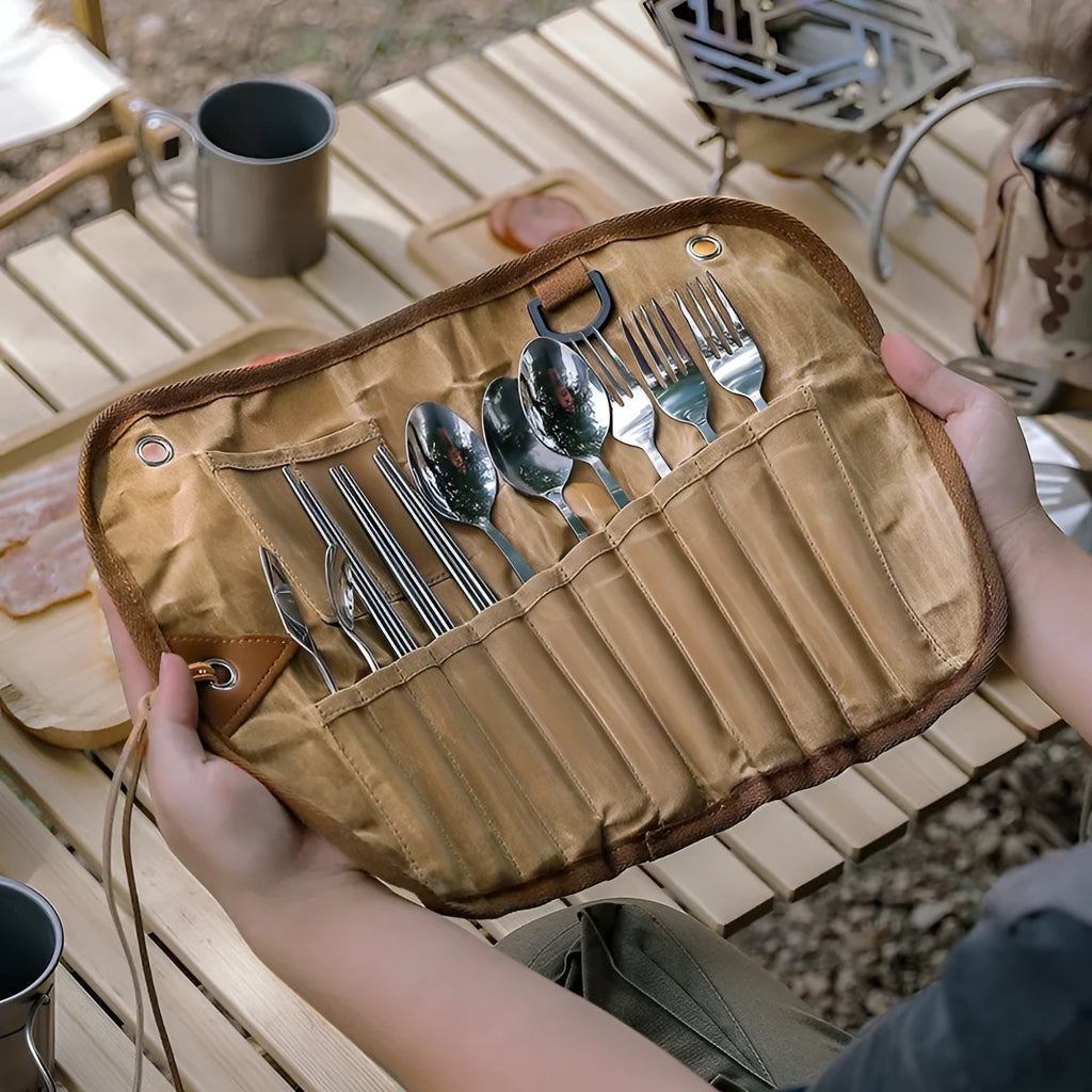 Green waxed canvas storage bag containing a wooden handle cutlery set for outdoor use.
