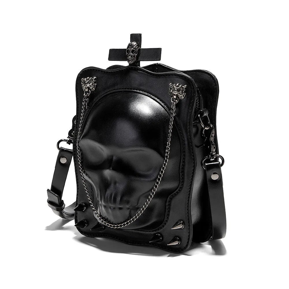Black vertical square mini crossbody bag with embossed skull design, metal chain strap, and zipper closure