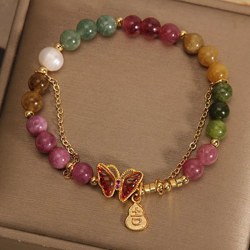 Close-up of a jade and tourmaline coloured agate bracelet with a butterfly-shaped gourd charm.