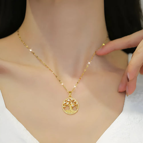 Close-up of a gold necklace with an ornate tree pendant featuring sparkling crystals and a white mother-of-pearl centre, on an adjustable chain.