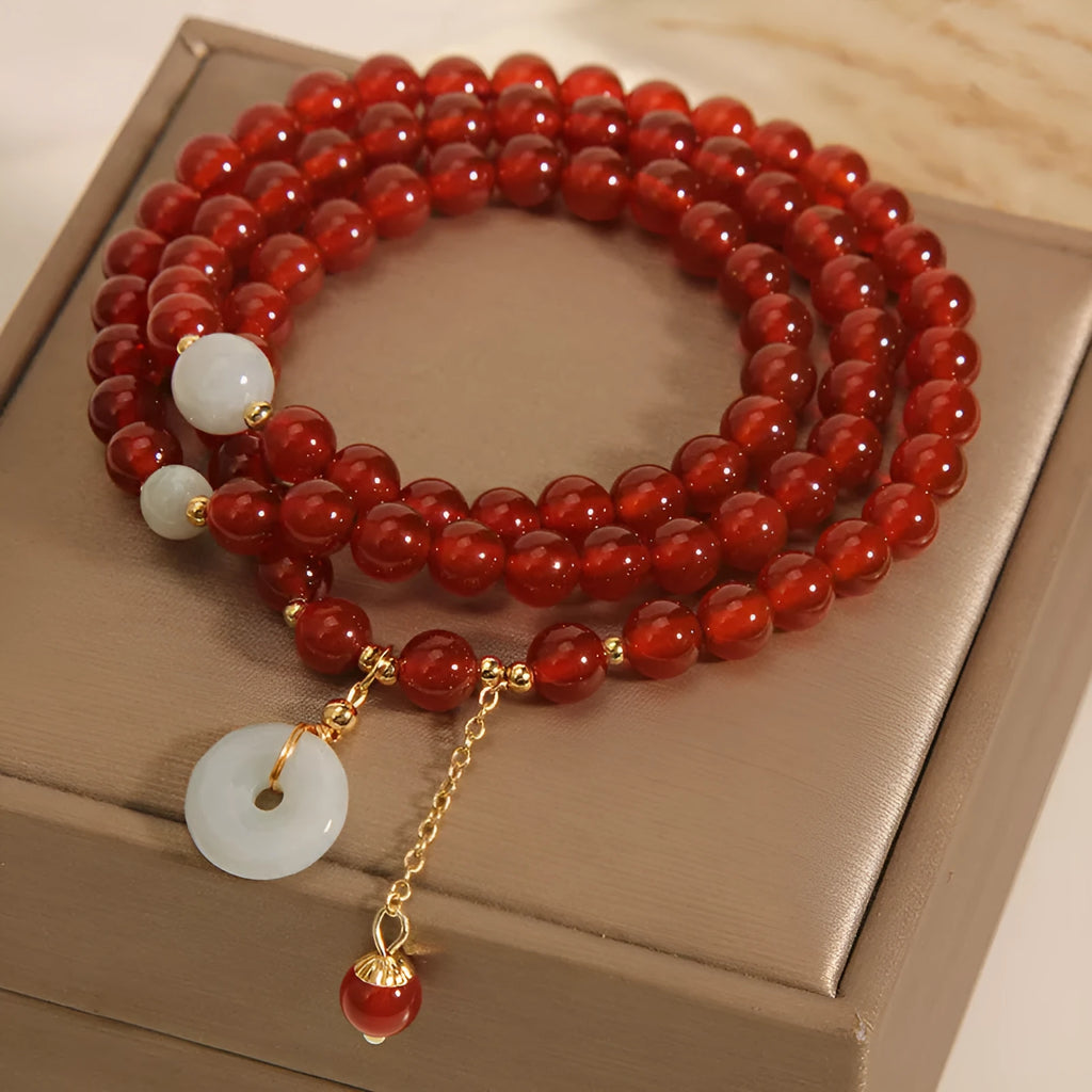 Women's multi-layer red agate crystal bracelet with adjustable closure on a wrist.