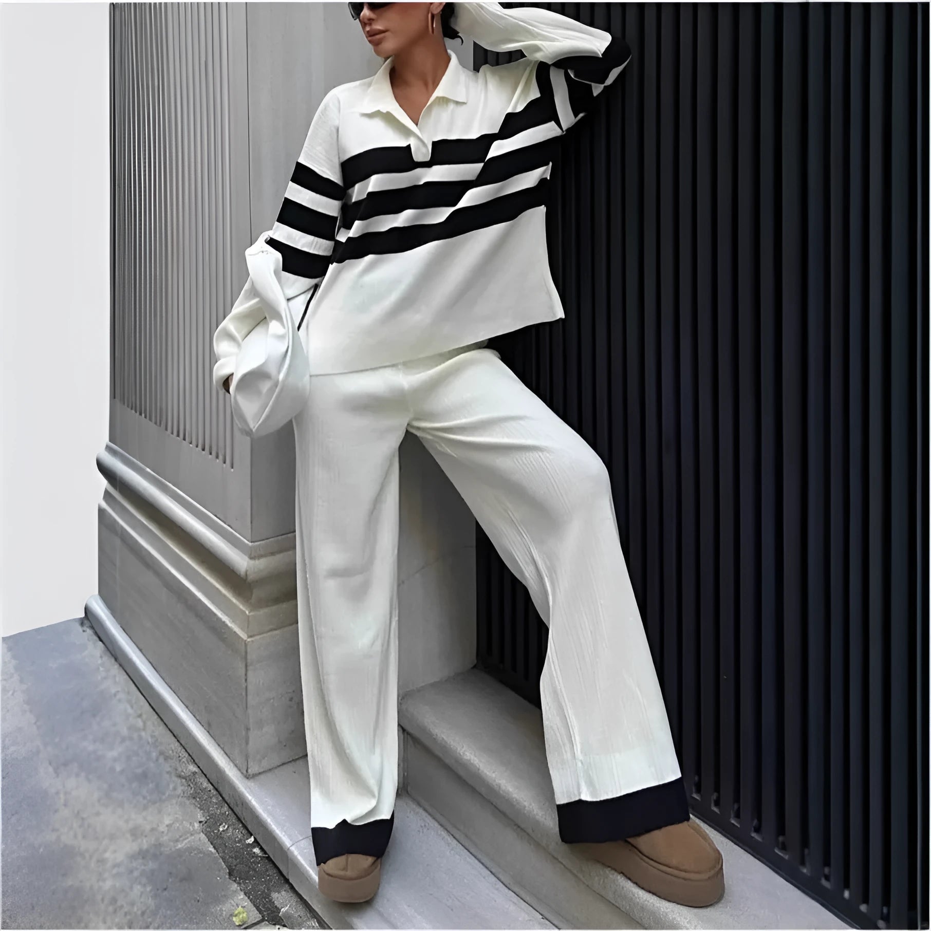 Women's black and white striped knitted polo shirt with long sleeves paired with matching trousers.