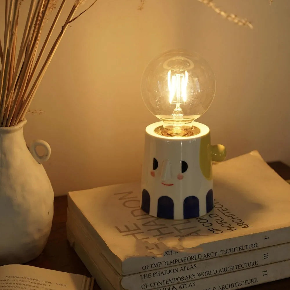 Off-white handmade ceramic table lamp with a rounded shape on a wooden surface.