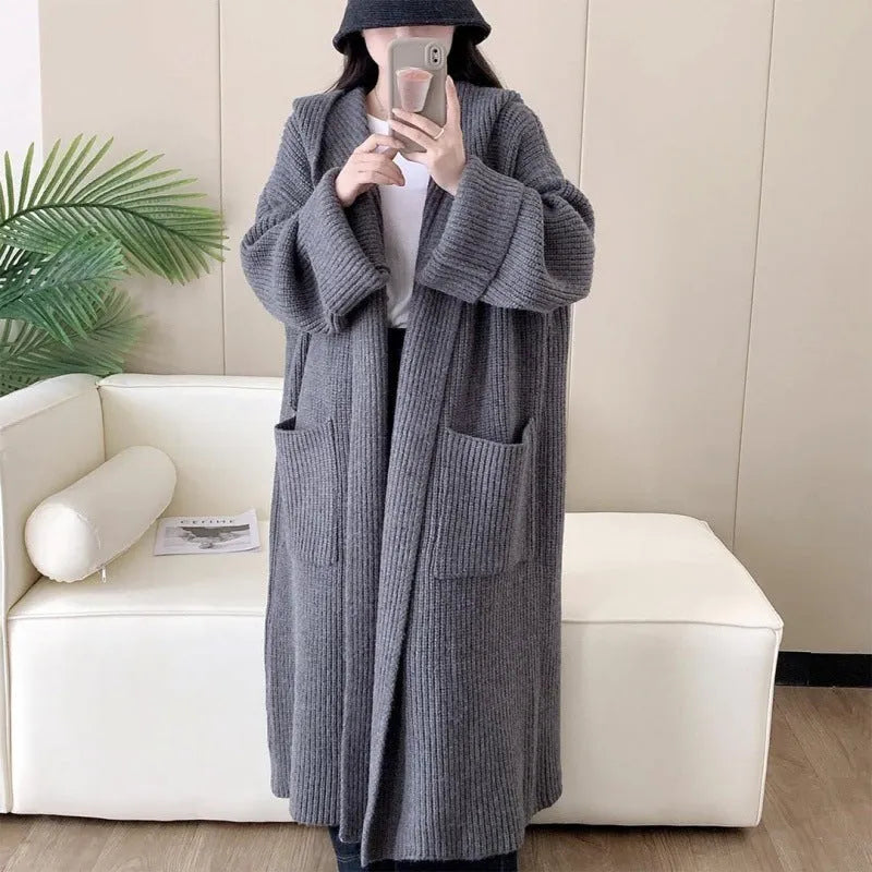 Woman wearing a long loose hooded cardigan coat in acrylic fabric, open as a cardigan.
