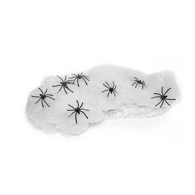 White cotton spider web Halloween decoration draped with plastic spiders on a dark background.