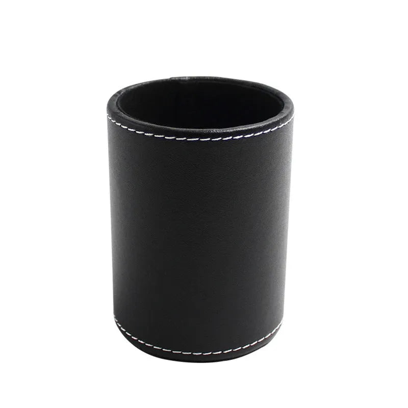 Round black leather pen container on a desk holding pens and pencils.