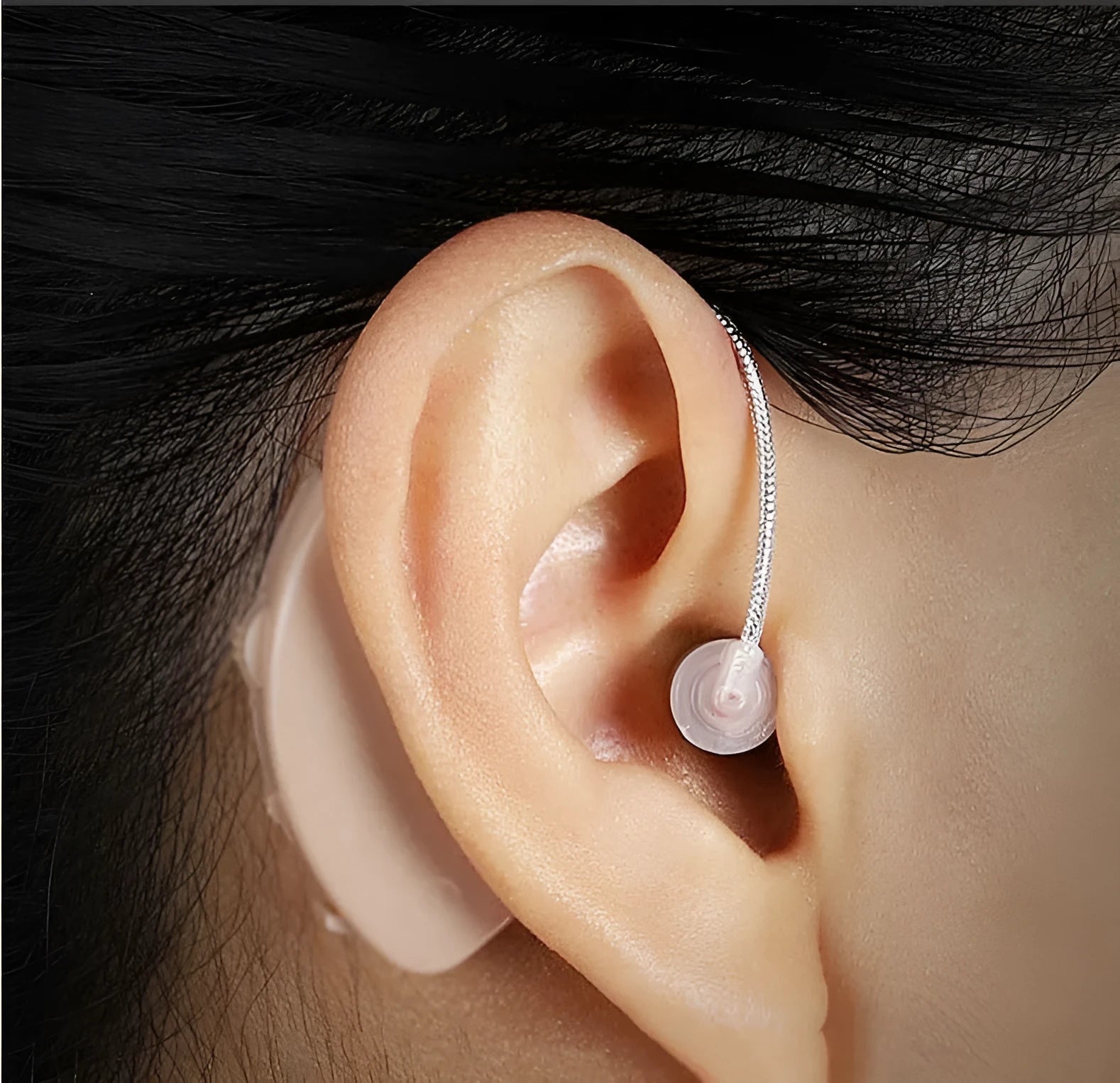 Black rechargeable hearing aid amplifier with silicone earplugs and a charging cable.