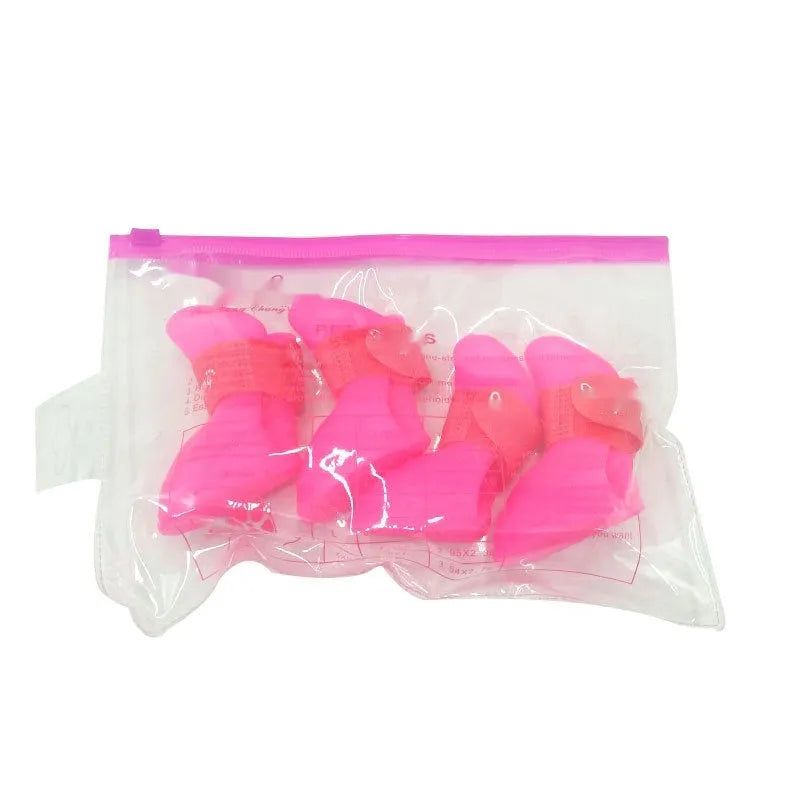 Set of four soft-soled rubber rain shoes for dogs in various colours on a wet surface.