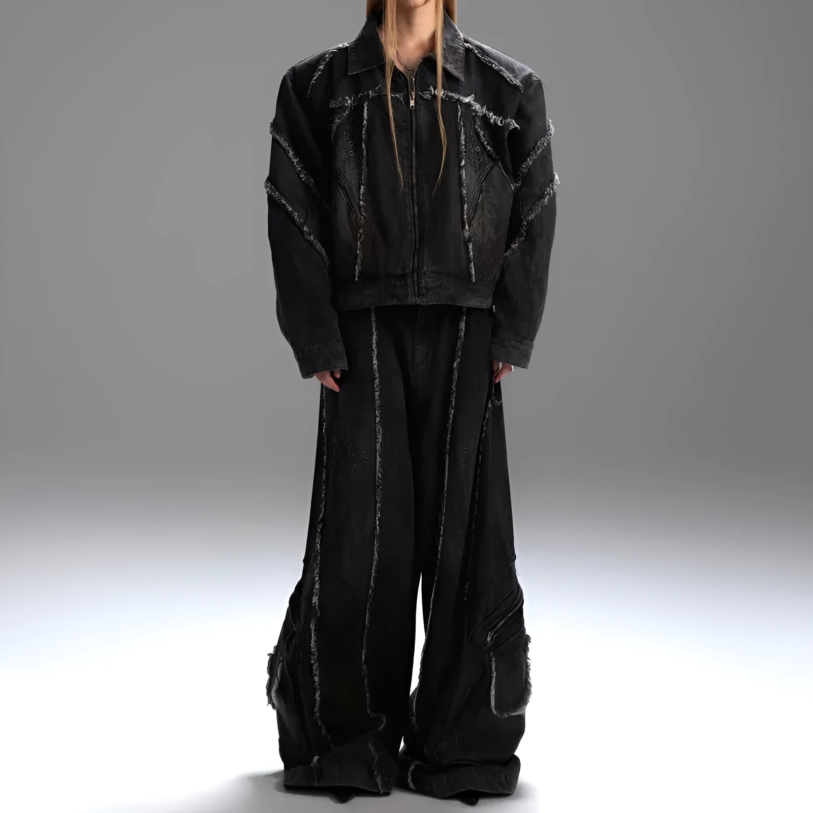 Black raw edge splash-dye distressed denim coat with padded shoulders and matching pants laid flat.