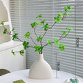 Artificial silk flower arrangement in a glass bottle vase, suitable for indoor home decor on a table