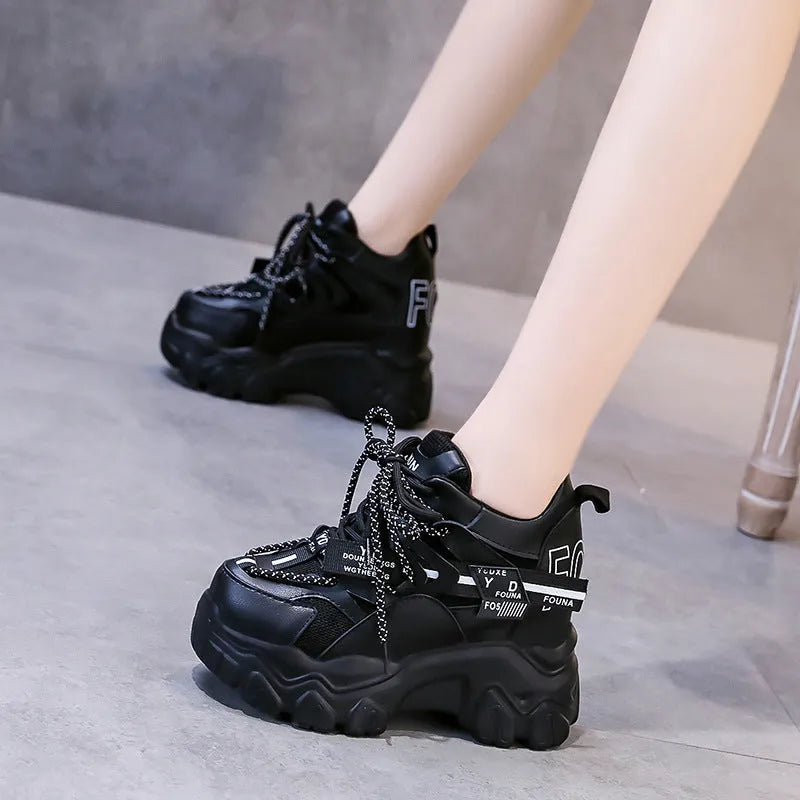 White women's low-top platform sports trainers with mesh panels and a black cross-strap on a rubber sole.
