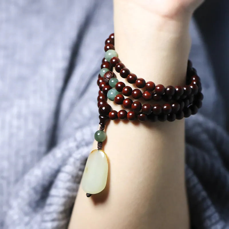 Close-up of a hand-carved rosewood beaded bracelet with 108 6mm beads and a carved Hotian jade pendant.
