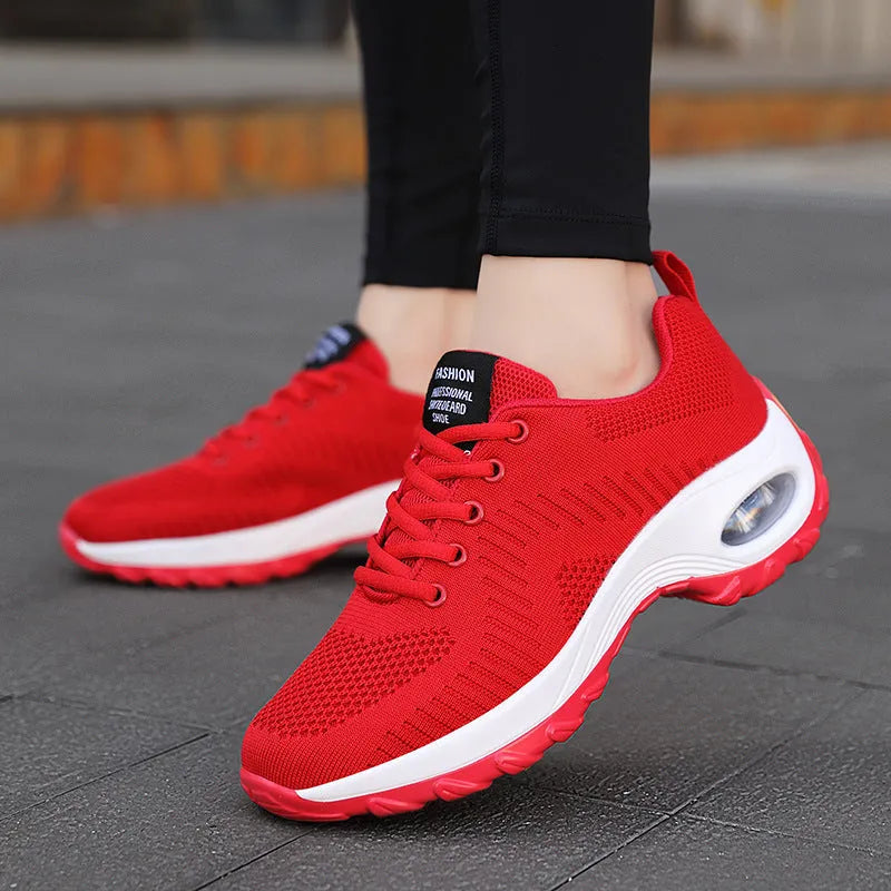 Red and black women's low-top mesh sneakers with round toe, front laces, and a mid heel on a white background.