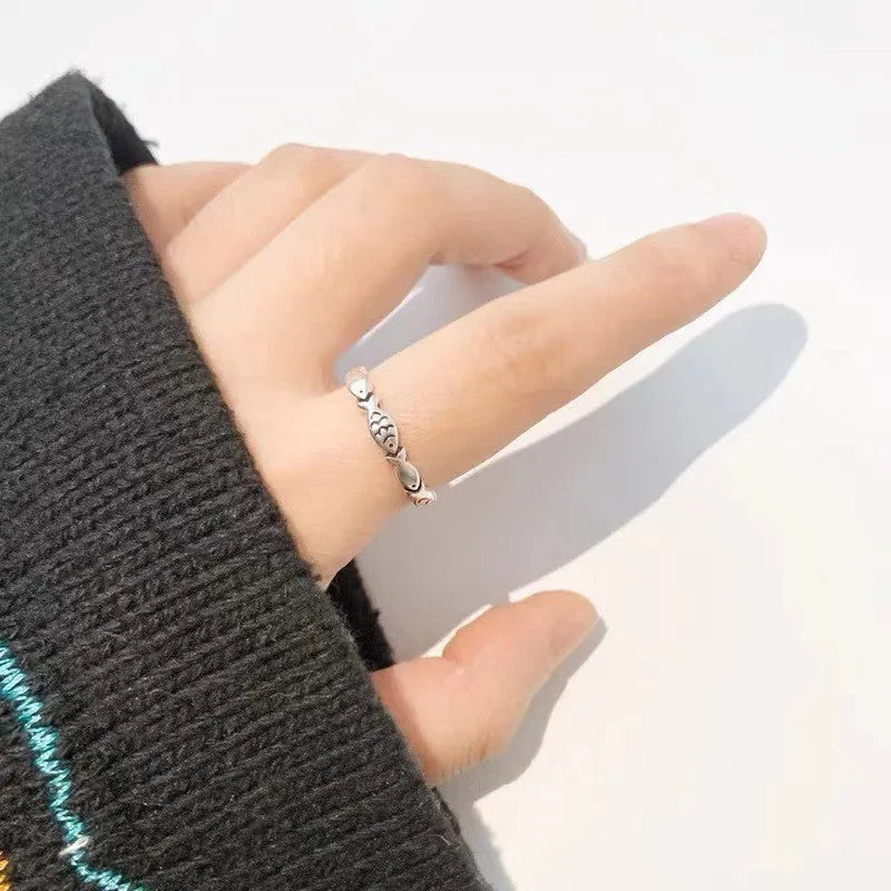 Close-up of a women's adjustable sterling silver ring with a vintage fish design on a finger.
