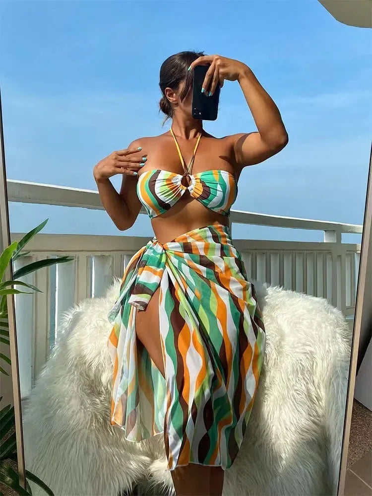 Women's yellow green printed bikini top and briefs with matching beach skirt laid flat.