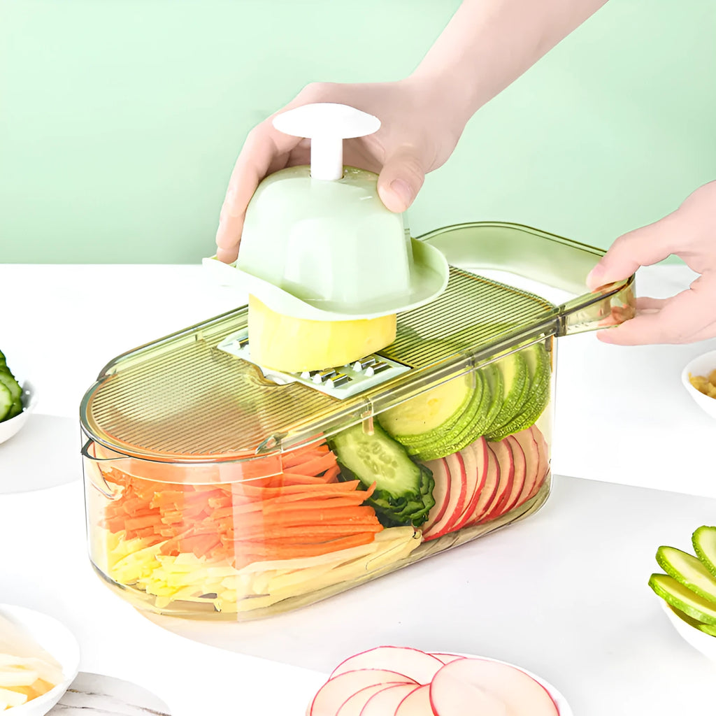 Transparent green vegetable chopper with multiple stainless steel blades and an optional white drain basket on a kitchen counter.