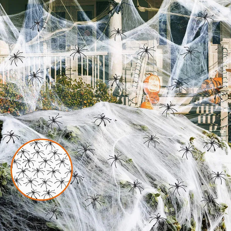 White cotton spider web Halloween decoration draped with plastic spiders on a dark background.