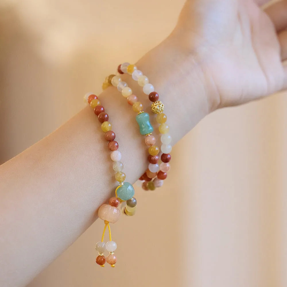 Women's handcrafted Jinsi Jade bracelet with pumpkin-shaped beads and tassels on a wrist.