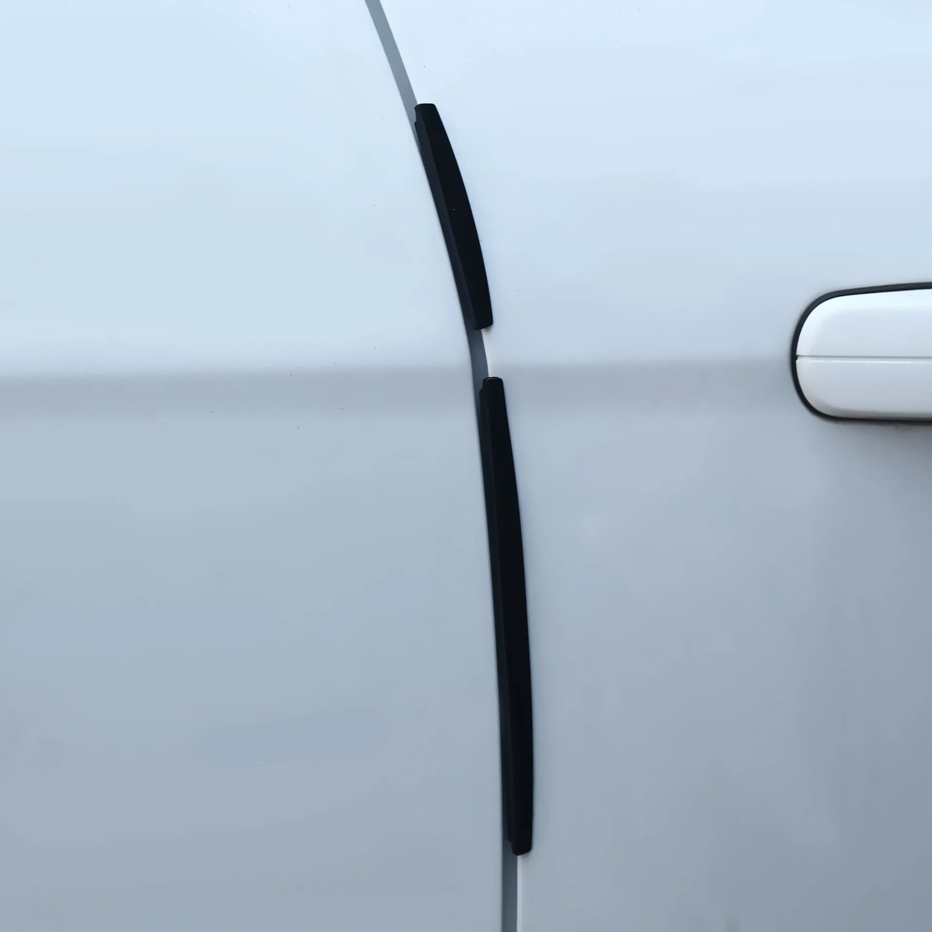 Close-up of a white flexible PVC car door edge protector strip on a roll, showing its profile and adhesive backing.