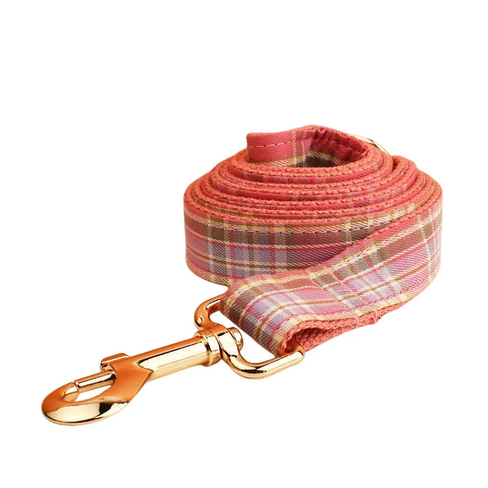 Plaid cloth dog collar and leash set with matching vest and decorative bow.
